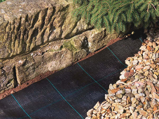 Image of weed fabric membrane installed under decorative stone in a landscaped garden